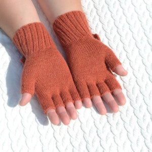 Hand knitted terracotta / copper alpaca convertible gloves with mitten flap on model's hands