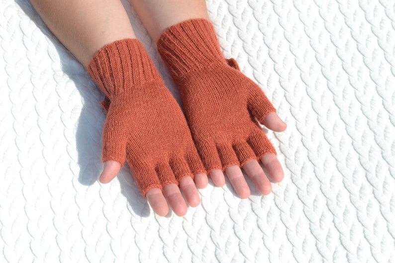 Hand knitted terracotta / copper alpaca convertible gloves with mitten flap on model's hands