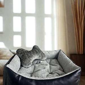 May include: A dog bed with a black faux leather exterior and a gray fabric interior. A bone-shaped pillow rests inside the bed. The bed is designed for comfort and style, suitable for small to medium-sized dogs.