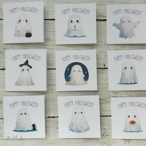 May include: Nine square Halloween greeting cards with cute ghost illustrations. Each card features a different ghost design, some with accessories like a witch hat or a pumpkin. The text "HAPPY HALLOWEEN!" is printed above each ghost.