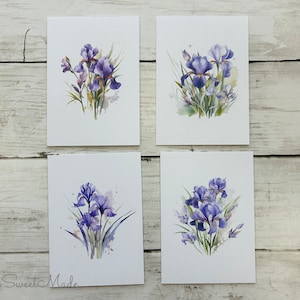 May include: Set of four watercolor prints featuring purple iris flowers on a white background. Each print depicts a different arrangement of irises with green leaves and stems.