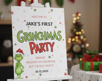 Könnte beinhalten: Ein weißes Staffeleischild mit dem Text "WELCOME TO JAKE'S FIRST GRINCHMAS PARTY" in Grün und Rot. Eine Illustration der Figur des Grinch befindet sich auf dem Schild. Ein grüner Kuchen mit Grinch-Topper und verpackten Geschenken stehen auf einem Tisch.
