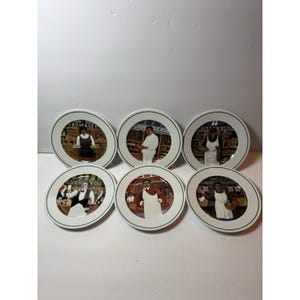 Könnte beinhalten: Set aus sechs weißen Keramikplatten mit grünem Rand. Jede Platte zeigt eine andere Illustration eines Ladenbesitzers in einem Geschäft, mit französischem Text. Die Teller sind rund und haben ein klassisches Design.