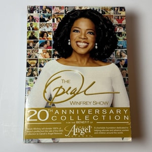 May include: The Oprah Winfrey Show 20th Anniversary Collection DVD set. The cover features a smiling Oprah Winfrey, with a collage of images in the background. The text reads "The Oprah Winfrey Show" and "20th Anniversary Collection".