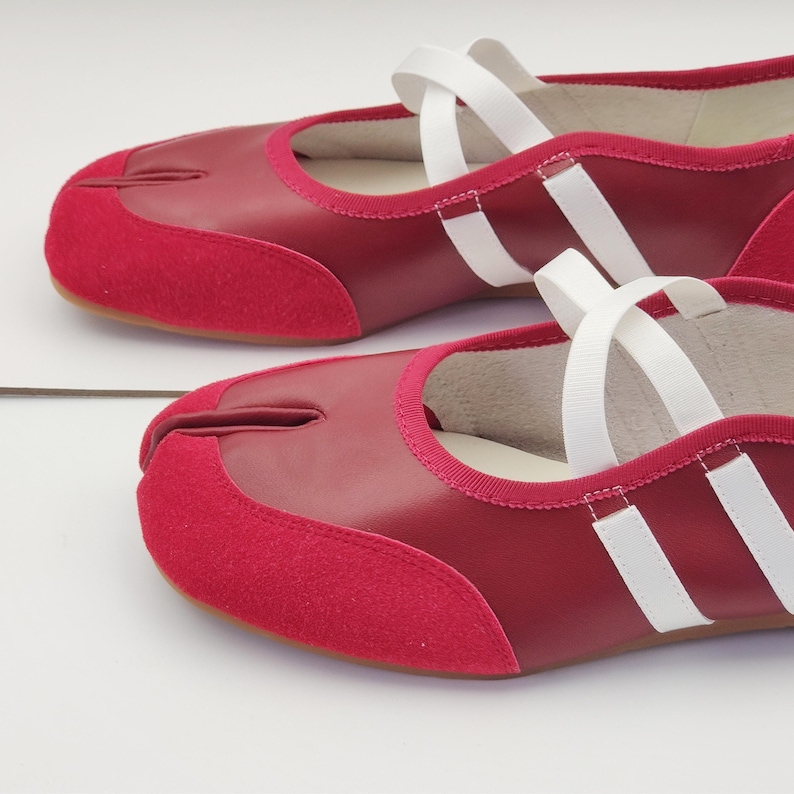 Puede incluir: Un par de zapatos rojos con puntera dividida y correas blancas. Los zapatos tienen una puntera de ante y una parte superior de cuero. La suela es de color marr&oacute;n claro. Los zapatos est&aacute;n dise&ntilde;ados con un dise&ntilde;o &uacute;nico de puntera dividida.