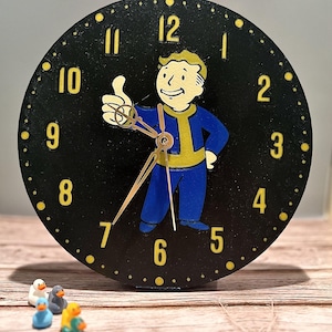 May include: A black round clock with a cartoon character in blue and yellow. The clock face has yellow numerals and dots. The clock hands are gold. Small, colorful duck figurines are in the foreground.
