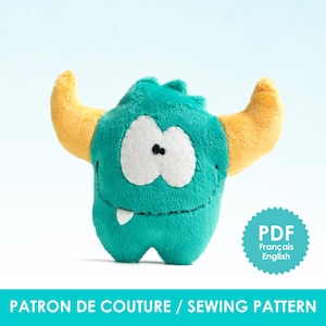 May include: A plush turquoise monster toy with large white eyes, a small black nose, and a single white tooth. It has two yellow horns and the text "PATRON DE COUTURE / SEWING PATTERN" at the bottom. A blue and white PDF icon is in the corner.