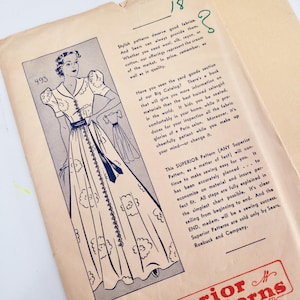 Op de afbeelding: Een vintage naaipatroon-envelop van lichtbruin papier met een blauwe inktillustratie van een lange jurk met pofmouwen en een knoopsluiting aan de voorzijde. De tekst bevat promotionele informatie voor Sears, Roebuck and Company en Superior Patterns.
