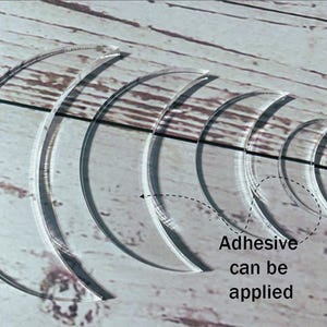 Könnte beinhalten: Transparente, gebogene Acrylschablonen in abgestuften Größen, angeordnet in Form eines Halbmonds. Der Text "Klebstoff kann aufgetragen werden" ist enthalten. Ideal für Bastel- und Designprojekte.