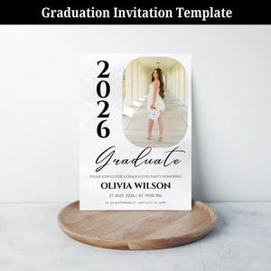 May include: A graduation invitation template with the year 2026 in large numbers. The invitation features a photo of a graduate in a white dress. The text reads "Graduate" and includes party details: Olivia Wilson, May 27, 2026, at 7:00 PM.