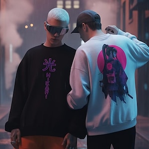 Może przedstawiać: Dwie osoby w deszczowej alejce ubrane w odzież uliczną. Jedna osoba ma na sobie czarną bluzę z japońskim tekstem i pomarańczowe szorty. Druga ma na sobie białą bluzę z grafiką na plecach. Aleja jest mokra i oświetlona latarniami.