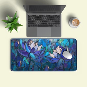 Könnte beinhalten: Eine Mausunterlage mit einem Buntglasdesign mit blauen und weißen Lotusblumen. Eine weiße Computermaus liegt auf der Matte. Ein Laptop und eine Tasse Kaffee sind im Hintergrund zu sehen. Das Design der Matte umfasst mehrere Blütenknospen.