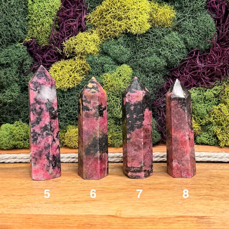 Puede incluir: Cuatro torres de piedras preciosas pulidas con patrones rosas y negros. Los cristales est&aacute;n numerados 5, 6, 7 y 8. El fondo presenta una mezcla de musgos verdes, amarillos y morados.