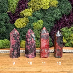 Puede incluir: Cuatro torres de piedras preciosas pulidas con puntas. Las piedras son principalmente rojas y negras, con algunos tonos grises y rosas. Los n&uacute;meros 9, 10, 11 y 12 est&aacute;n impresos en la base de cada torre. El fondo es una mezcla de musgos verdes, amarillos y morados.