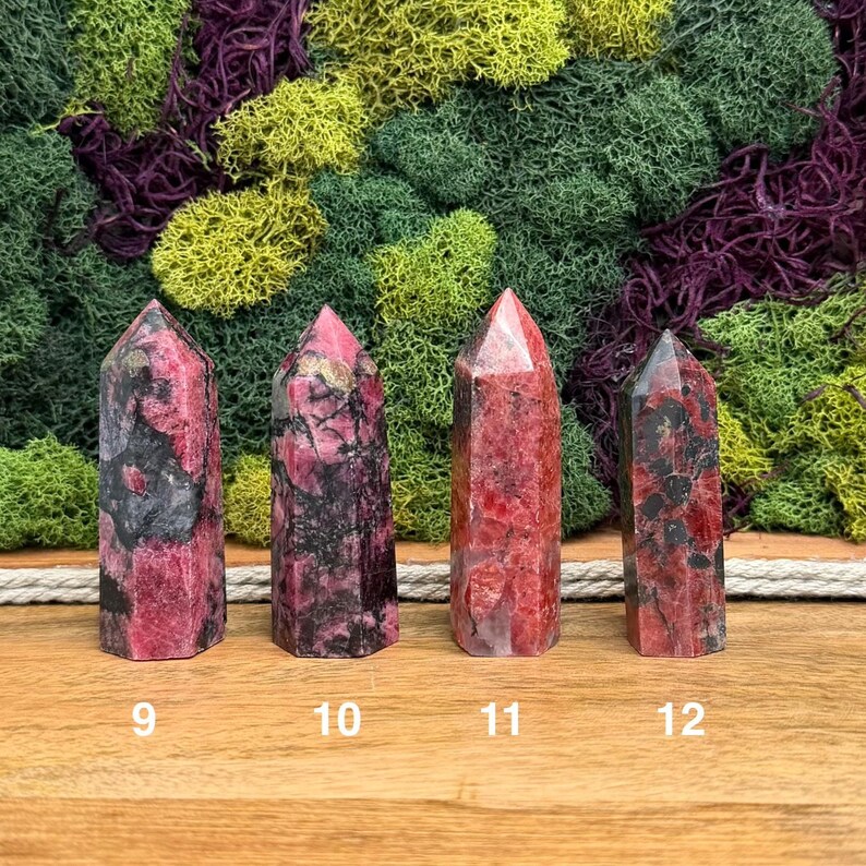 Puede incluir: Cuatro torres de piedras preciosas pulidas en tonos de rojo, rosa y negro, cada una con una parte superior puntiaguda. Las piedras est&aacute;n numeradas 9, 10, 11 y 12. El fondo presenta una mezcla de musgo verde, amarillo y morado.