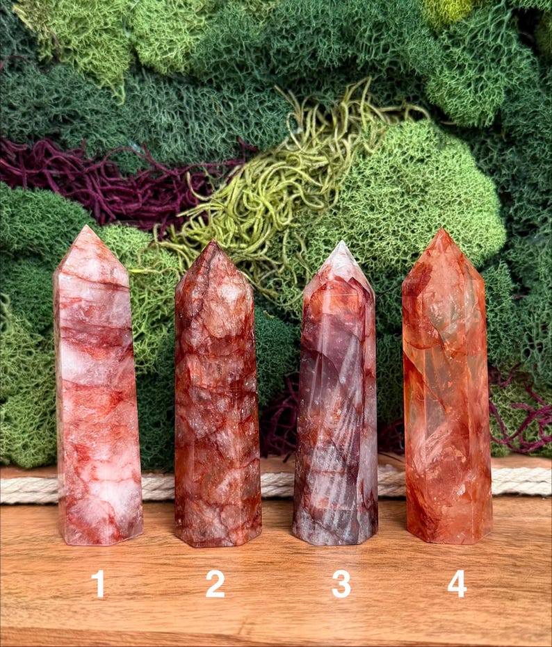 May include: Four red quartz crystal towers with varying patterns and hues. The crystals are numbered 1 through 4. The background features green and burgundy moss.