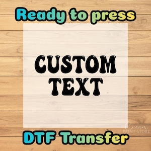 May include: A DTF transfer design with the words "Ready to press", "Custom Text", and "DTF Transfer" in a retro font. The design is on a white background with a wooden plank backdrop.