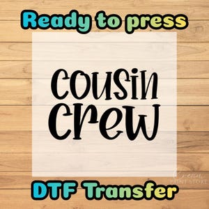 May include: A DTF transfer design with the words "Ready to press" in a teal and green font at the top. The words "Cousin Crew" are in a bold, black font in the center. The words "DTF Transfer" are in a teal and yellow font at the bottom.