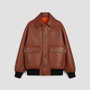 May include: A brown leather jacket with a collared neckline, two front pockets, and black ribbed cuffs. The jacket has a button-up closure and an orange quilted lining. A classic bomber style.