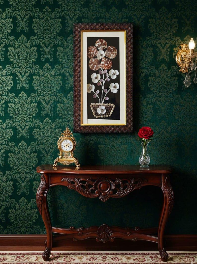 K&ouml;nnte beinhalten: Ein gerahmtes Kunstwerk mit einem floralen Arrangement aus Muscheln, &uuml;ber einem Holztisch. Eine goldene Uhr und eine Vase mit einer roten Rose stehen auf dem Tisch. Der Hintergrund ist eine dunkelgr&uuml;ne Tapete mit Muster.