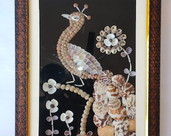 Könnte beinhalten: Gerahmtes Kunstwerk mit einem Pfau aus verschiedenen Muscheln. Der Pfau ist vor einem schwarzen Hintergrund platziert, wobei weiße und beige Muscheln seinen Körper und Schwanz bilden. Der Rahmen ist dunkelbraun mit einem strukturierten Muster und einem goldenen Innenrand.