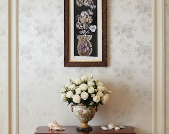 May include: A framed artwork with seashell designs hangs above a mahogany console table. The table has gold detailing and a vase of white roses. Seashells are placed on the table, creating a coastal theme. The table is approximately 120 cm long.