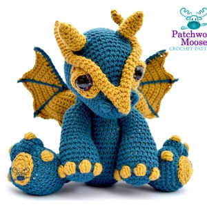 Könnte beinhalten: Ein gehäkelter blauer und gelber Drache mit großen Augen. Der Drache sitzt mit ausgebreiteten Flügeln. Der Drache ist ein handgemachtes Amigurumi-Spielzeug.