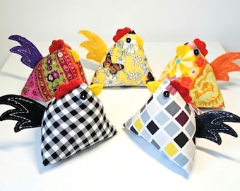 May include: Five fabric chicken-shaped ornaments featuring various patterns including black and white gingham, a yellow butterfly print, a floral print, a multi-colored geometric grid, and a pink and green paisley design, each with a red felt comb.