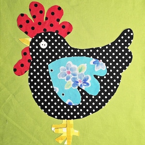 May include: A fabric chicken applique on a green background. The chicken has a black body with white polka dots, a red comb with black dots, and a blue floral belly. The beak is yellow, and the feet are yellow and white.