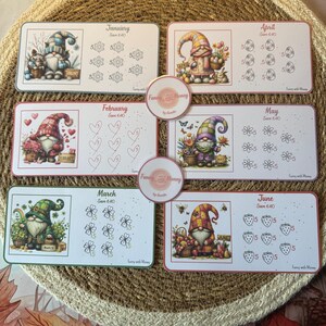 Puede incluir: Conjunto de seis tarjetas mensuales de desafío de ahorro con ilustraciones de gnomos. Cada tarjeta tiene un tema diferente, incluyendo copos de nieve, corazones, flores y fresas. Las tarjetas son rectangulares.