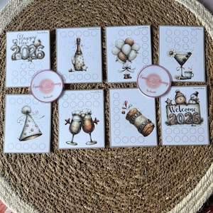Puede incluir: Un conjunto de tarjetas ilustradas y pegatinas con temática festiva. Las tarjetas presentan imágenes de botellas de champán, globos y gorros de fiesta, con los textos "Happy New 2026" y "Welcome 2026". Las pegatinas tienen el texto "Funny with Money".