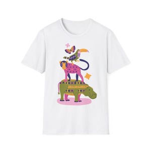 Pode incluir: Camiseta branca com uma ilustração extravagante de um tucano, macaco, borboleta e hipopótamo empilhados uns sobre os outros. Os animais são decorados com padrões coloridos. A camiseta tem gola redonda.
