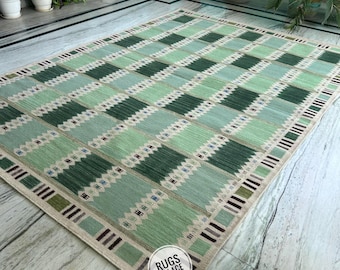 May include: A rectangular green and beige rug with a geometric pattern. The rug features alternating squares of light and dark green, with a beige border and the text "RUGS PALACE" on the corner.