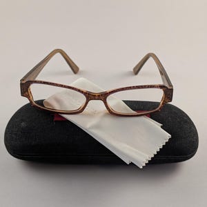 May include: A white ceramic mug with a black handle and the text "But First, Coffee" in a black, handwritten-style font. The mug is on a white surface.