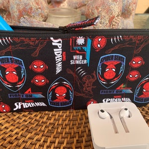May include: Black zippered pouch with a Spiderman theme. The pouch has a repeating pattern of Spiderman's face, the words "Spider Sense", "Fight On", and "Web Slinger".