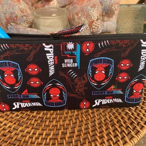 May include: Black zippered pouch with a repeating pattern of Spider-Man logos, including "Spider Sense", "Web Slinger", and "Fight On".