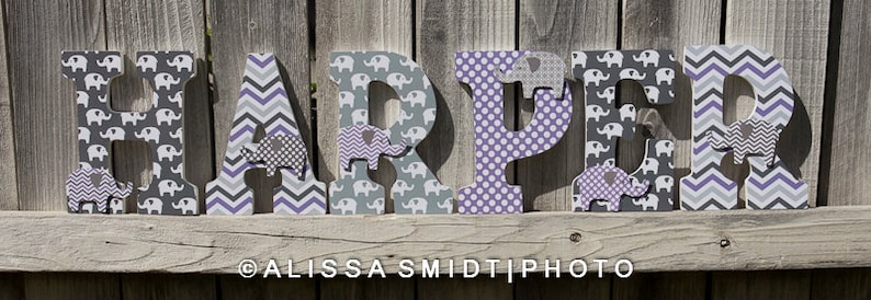 May include: Wooden letters spelling the name "HARPER" decorated with a gray and purple elephant print, chevron pattern, and polka dots.