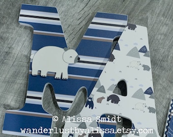 May include: Wooden letters spelling "MA" decorated with a blue and white striped pattern and a white polar bear on the "M". The "A" features a white background with a pattern of gray mountains, white polar bears, and brown bears.