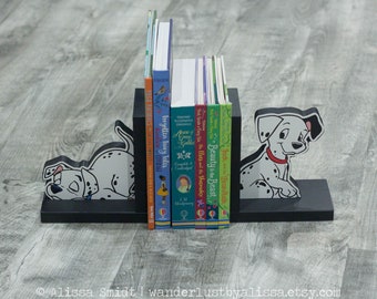 May include: Black bookends shaped like Dalmatian dogs holding up a stack of children's books. The books include titles like "Beauty and the Beast", "Jack and the Beanstalk", and "Anne of Green Gables".