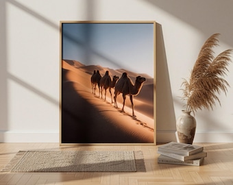May include: A framed wall art print featuring a desert landscape with a line of four camels walking across golden sand dunes under a clear sky. The image captures the warm light and shadows of the desert, presented in a simple wooden frame.