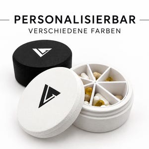 Könnte beinhalten: Ein runder Pillenorganizer mit sieben Innenfächern, die verschiedene Kapseln enthalten. Ein weißer Behälter ist mit passendem Deckel geöffnet, ein schwarzer Behälter ist geschlossen. Beide Deckel zeigen ein schwarzes oder weißes Dreieckslogo.