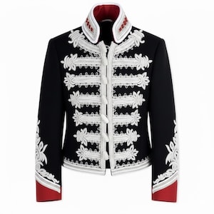 Puede incluir: Chaqueta negra con bordados florales blancos y ribetes plateados. La chaqueta presenta un cuello alto con forro y puños rojos. La parte delantera tiene detalles decorativos blancos en forma de cuerda y diseños florales ornamentados.