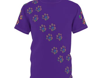 May include: A purple t-shirt with a pattern of colourful paw prints. The paw prints are arranged diagonally across the front. The sleeves also have colourful accents.