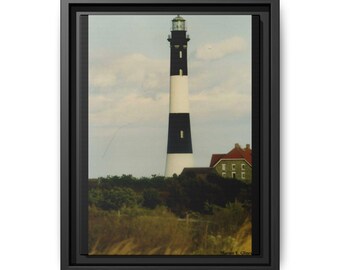 Puede incluir: Impresión en lienzo enmarcada que presenta un faro alto con rayas blancas y negras. El faro se alza contra un cielo nublado, con un edificio de tejado rojo y vegetación verde en su base. La obra de arte está dentro de un marco negro.