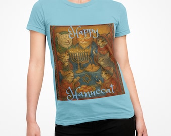 May include: Light blue t-shirt featuring a colorful illustration of cats celebrating Hanukkah. The image includes a menorah, a Star of David, and the text "Happy Hanuccat" in a decorative script. The cats are depicted in various poses around a table.