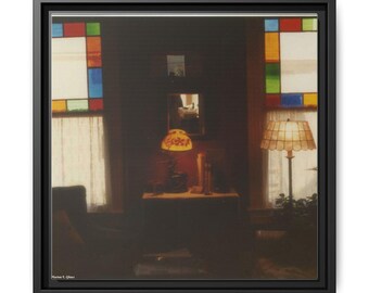 Puede incluir: Impresión en lienzo enmarcada de una escena interior con poca luz. La imagen presenta una mesa con una lámpara, un espejo y una vidriera con paneles rojos, azules, verdes y amarillos. La impresión está en un marco negro.
