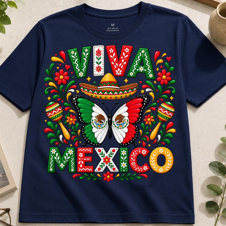 Pode incluir: Uma t-shirt azul-marinho de manga curta com uma estampa gr&aacute;fica com o texto VIVA MEXICO. O design inclui uma borboleta central com asas nas cores da bandeira mexicana, um sombrero, dois marac&aacute;s e padr&otilde;es florais coloridos.