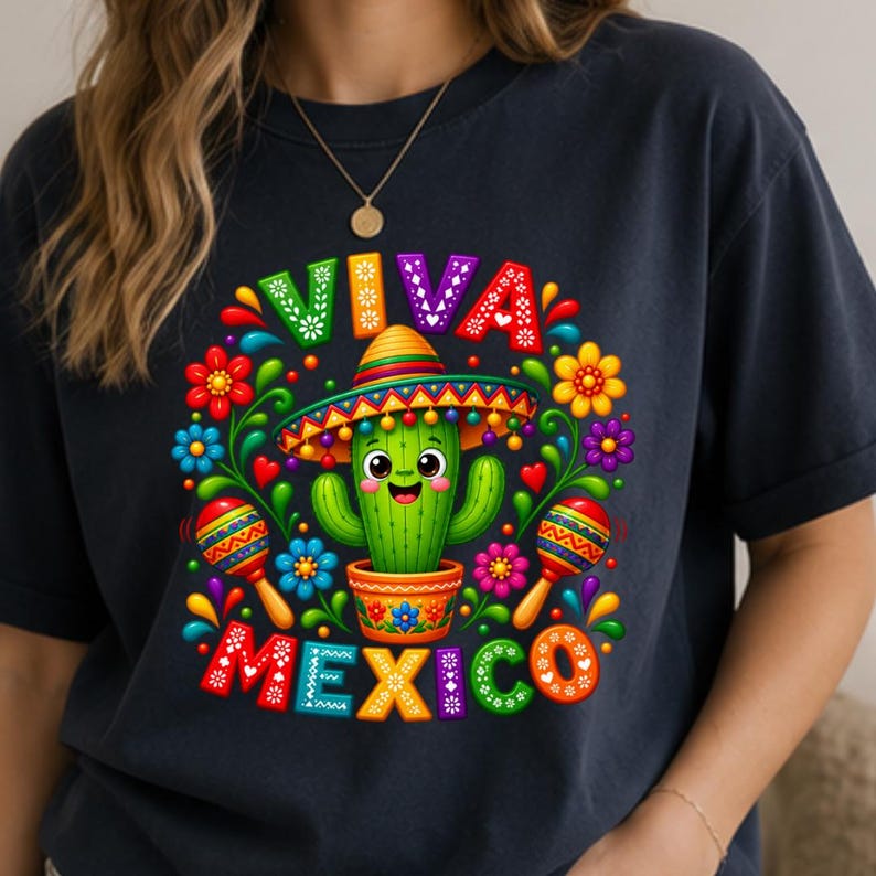 Pode incluir: Uma t-shirt azul-marinho escuro com um gr&aacute;fico colorido de um cacto verde sorridente usando um sombrero num vaso. O design inclui duas maracas, flores vibrantes e o texto VIVA MEXICO em letras grandes e multicoloridas &agrave; volta do cacto.