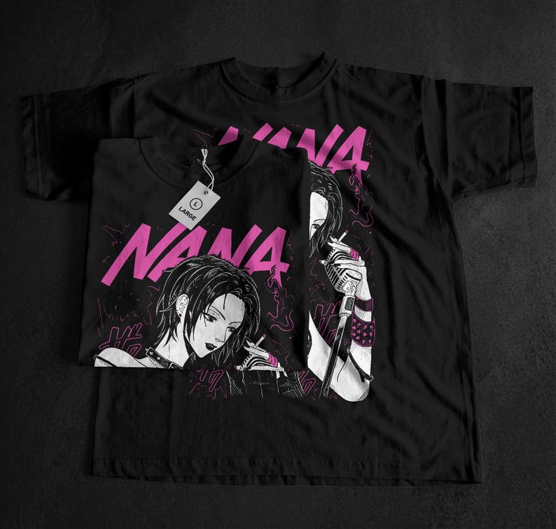 May include: Black t-shirts featuring a manga-style illustration of a woman with the word "NANA" in pink. One shirt is folded, with a tag that reads "LARGE". The design includes a microphone and smoking imagery.