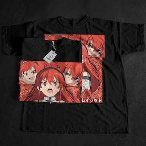 May include: Black t-shirt featuring a vibrant anime-style graphic of a character with red hair and eyes. The design includes multiple panels with different expressions and Japanese text. A white tag is attached to the shirt.